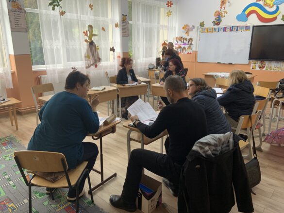 Working meeting to carry out the objectives of the project. This picture shows 8 adults sitting in benches and talking.